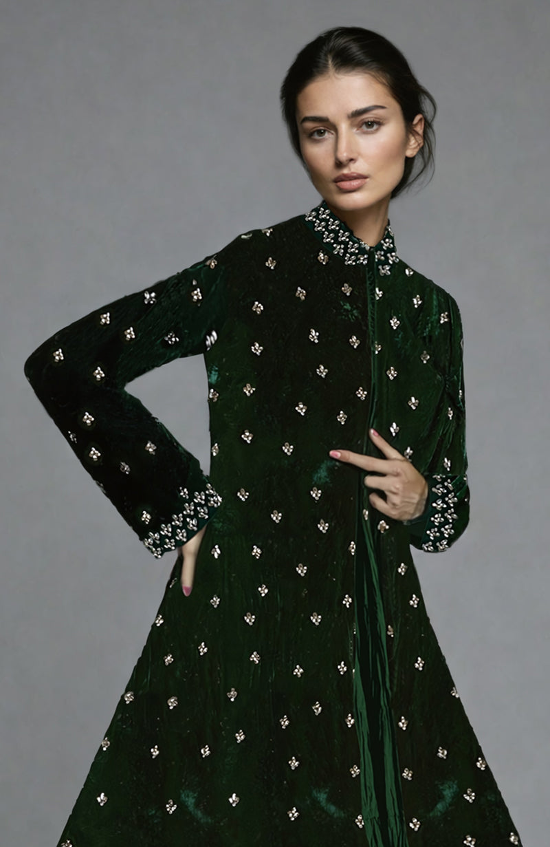 A woman models an emerald green velvet jacket with crystal embroidery and a high-low cut.