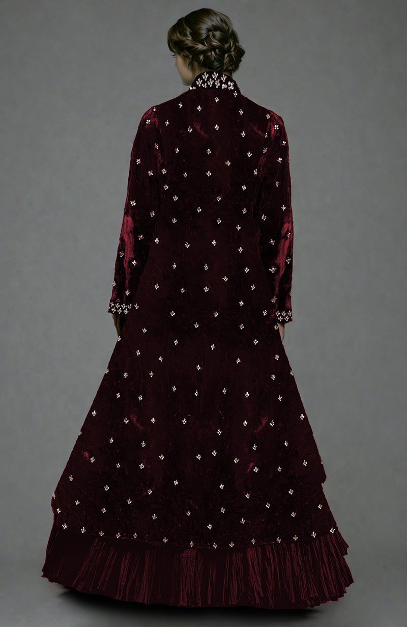 Rear view of a woman wearing a maroon velvet jacket with crystal embroidery and a tiered skirt.