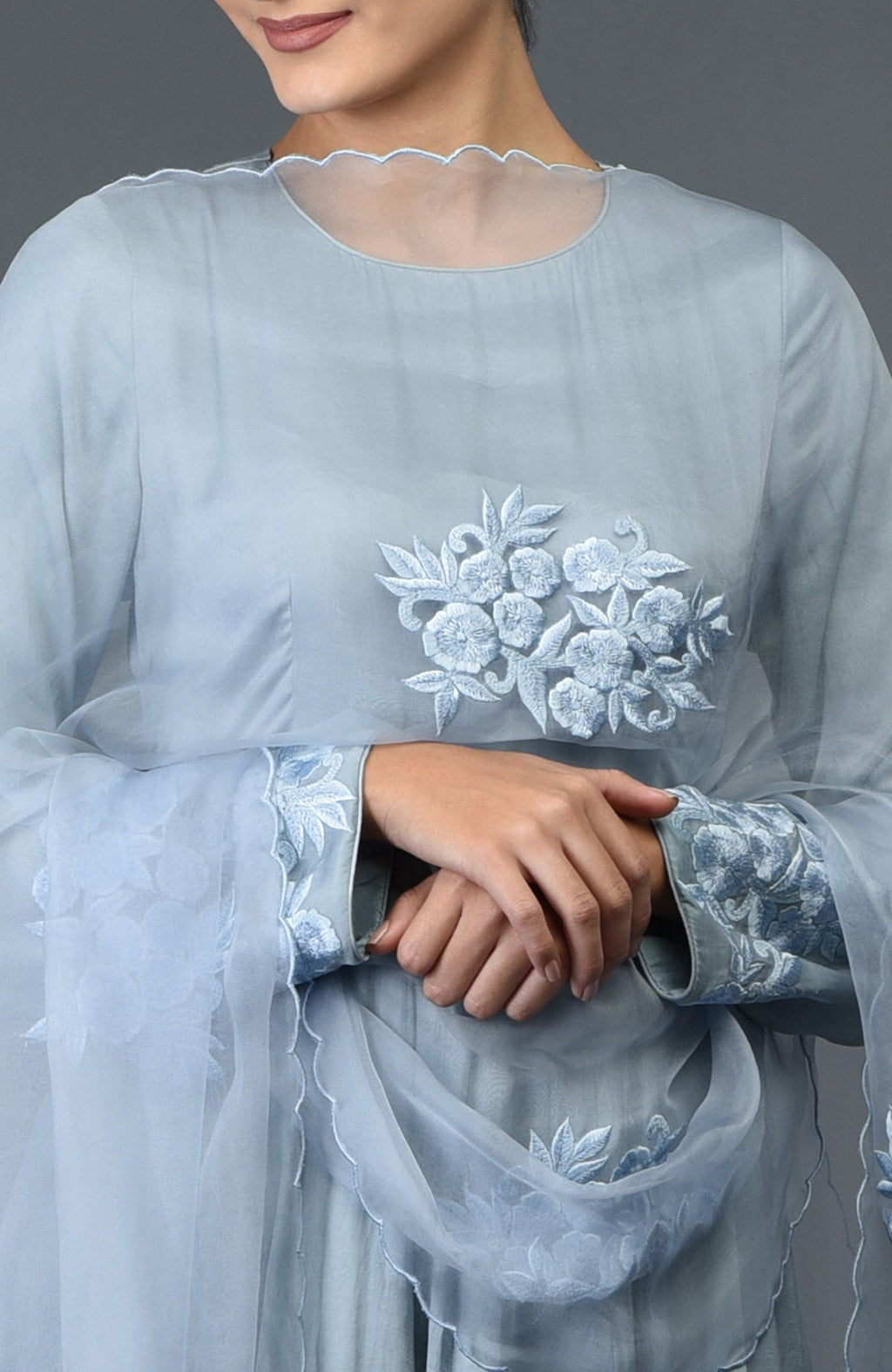 A woman models a powder blue floral embroidered anarkali suit with a matching dupatta.