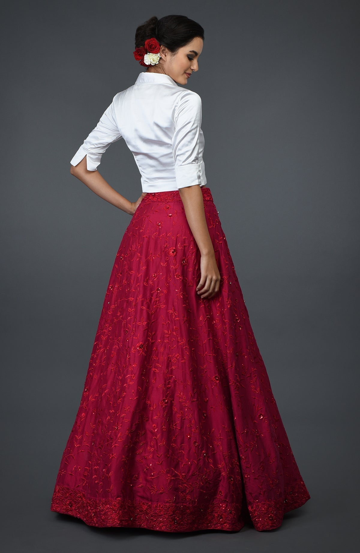 Woman in a white blouse and a red floral embroidered skirt with sequins.