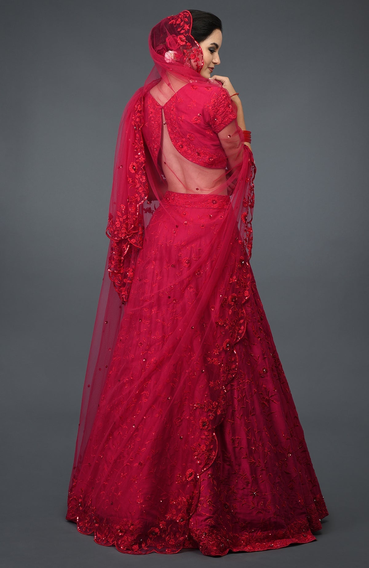 A woman models a red floral resham sequin and beads embroidered lehenga outfit.