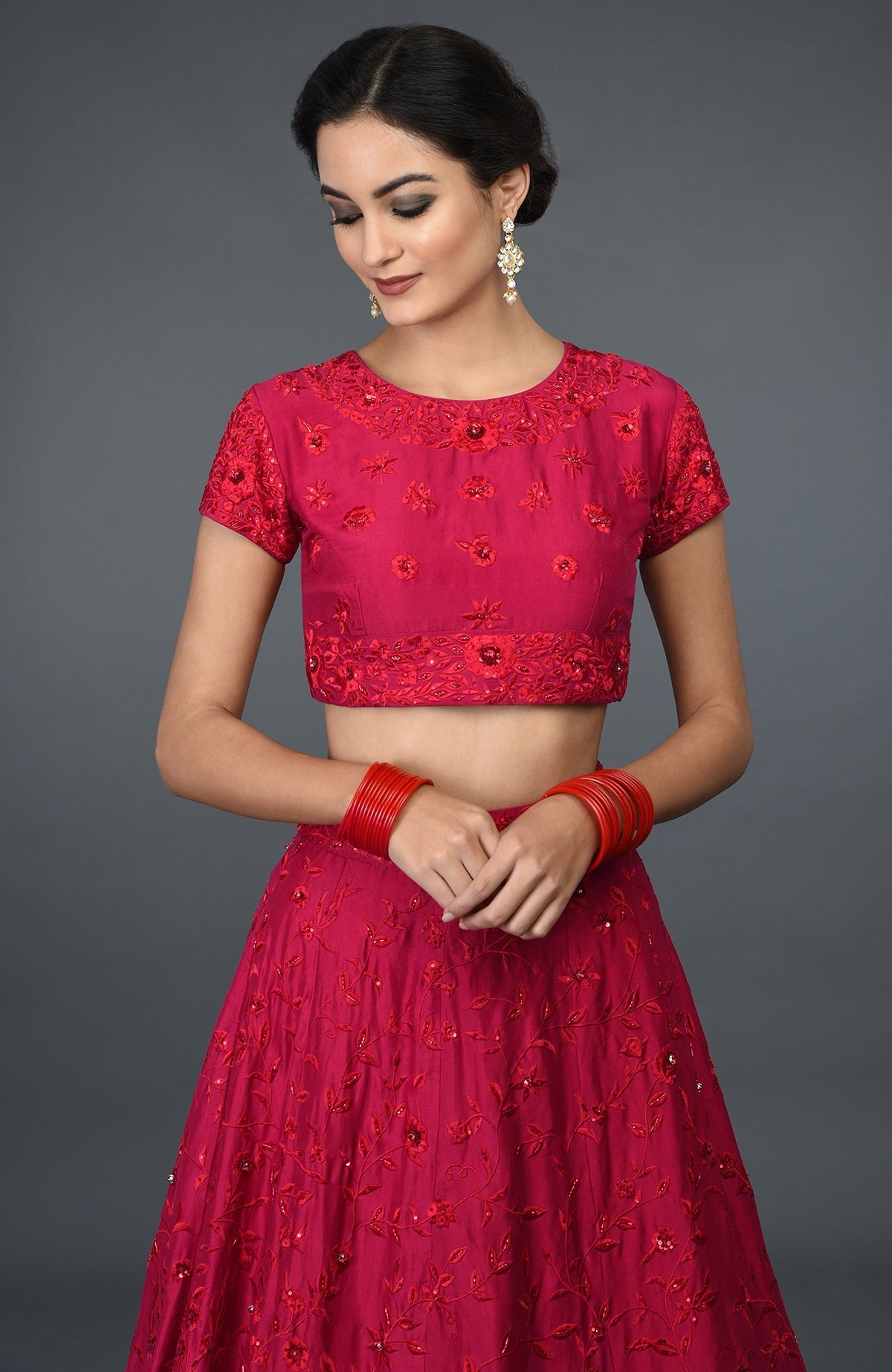 A woman models a red floral resham sequin and beads embroidered lehenga outfit.