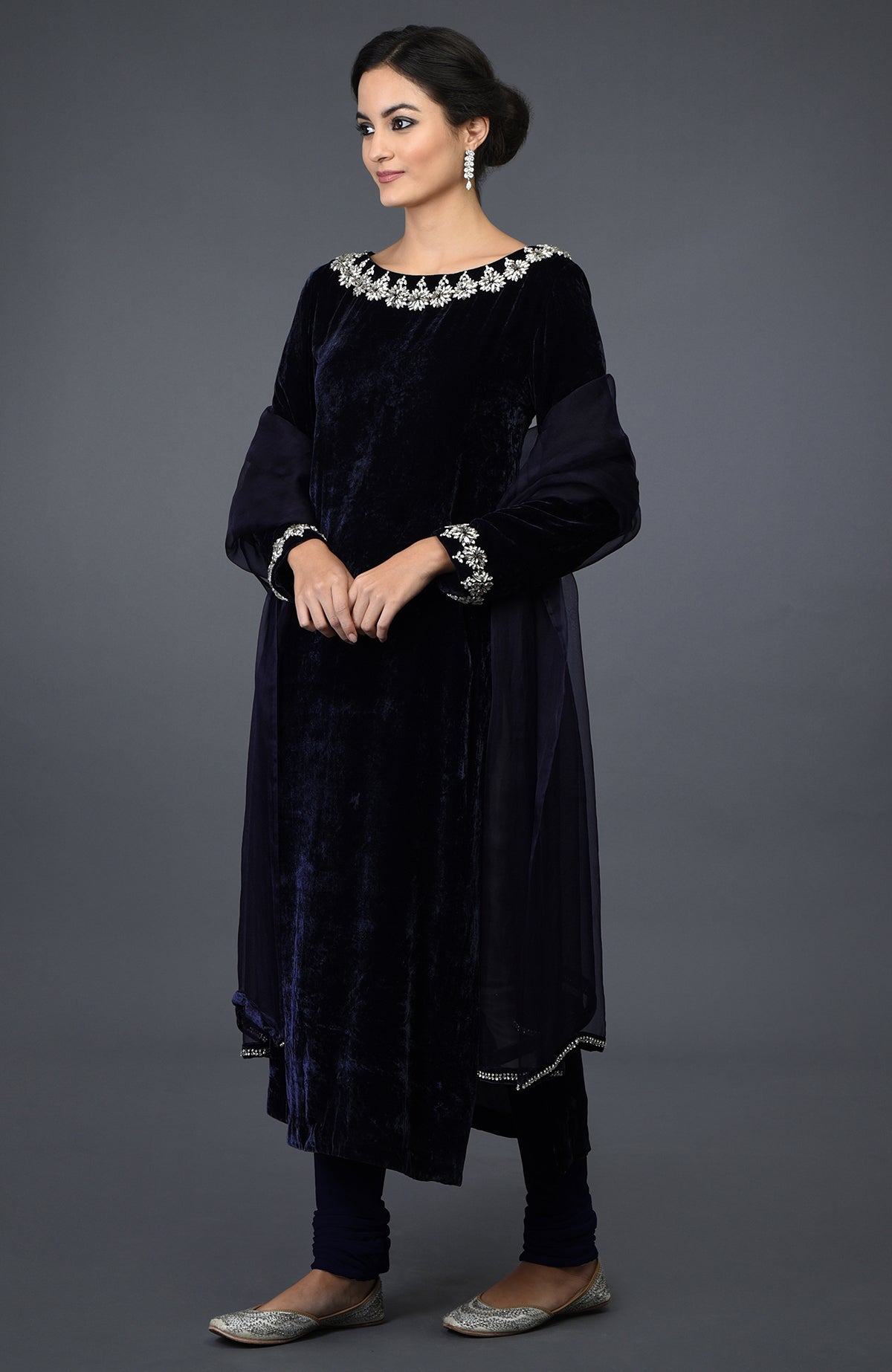 A woman models a midnight blue velvet suit with Swarovski embroidery and a sheer dupatta.