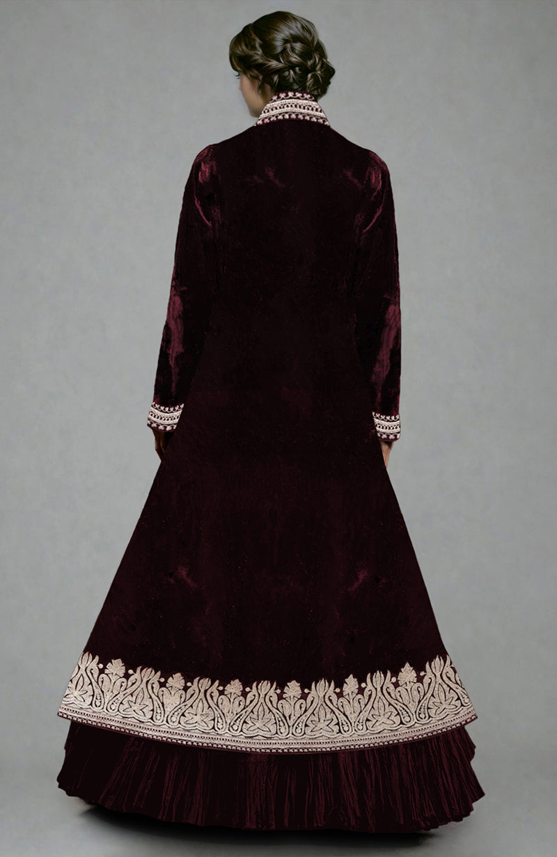 A woman from behind wears a maroon velvet jacket with silver embroidery and a tiered skirt.