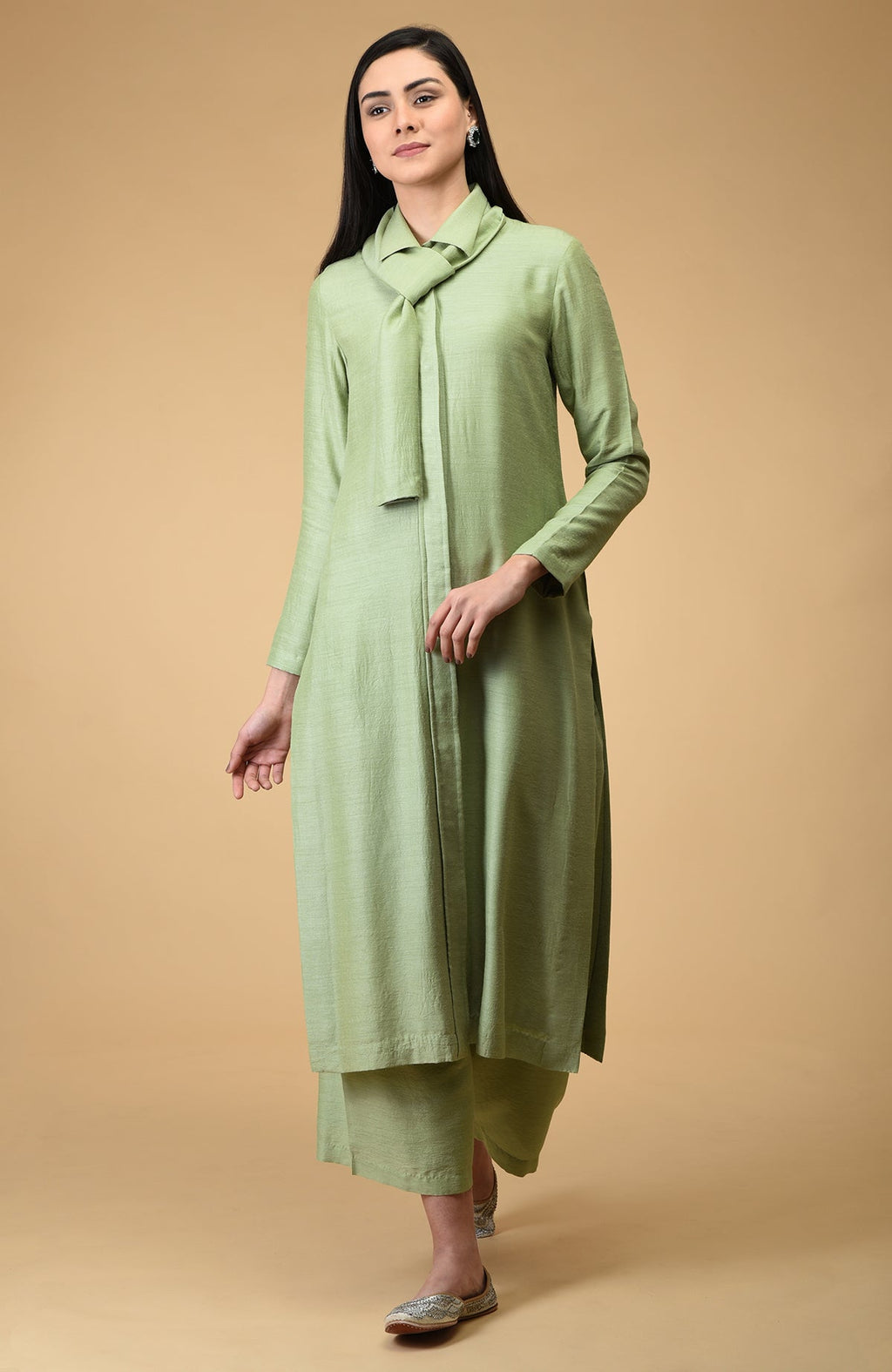 A woman models a sage tie-neck kurta set with wide-leg pants and embellished flats.
