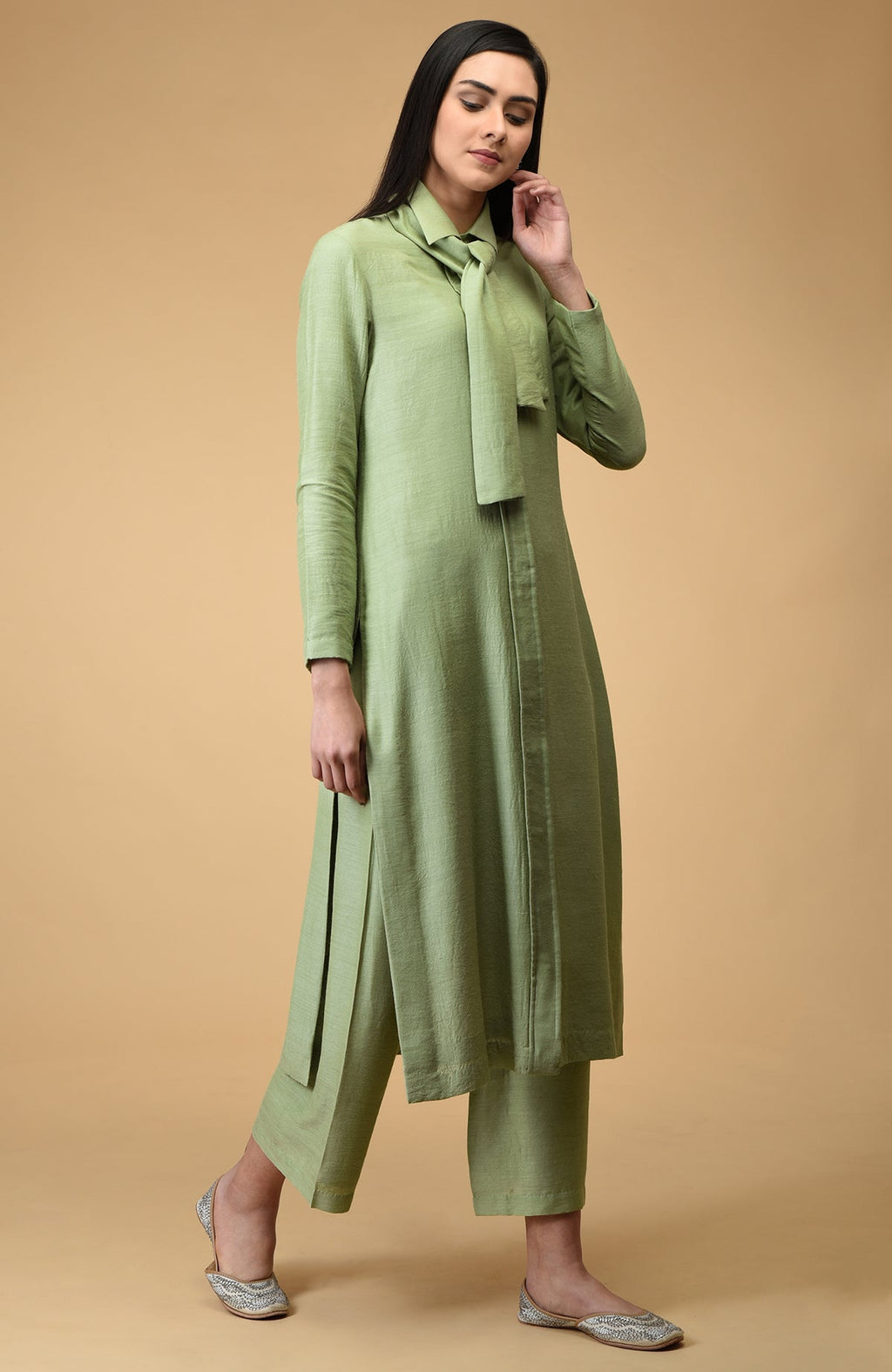 A woman models a sage tie-neck kurta set with embroidered flats.