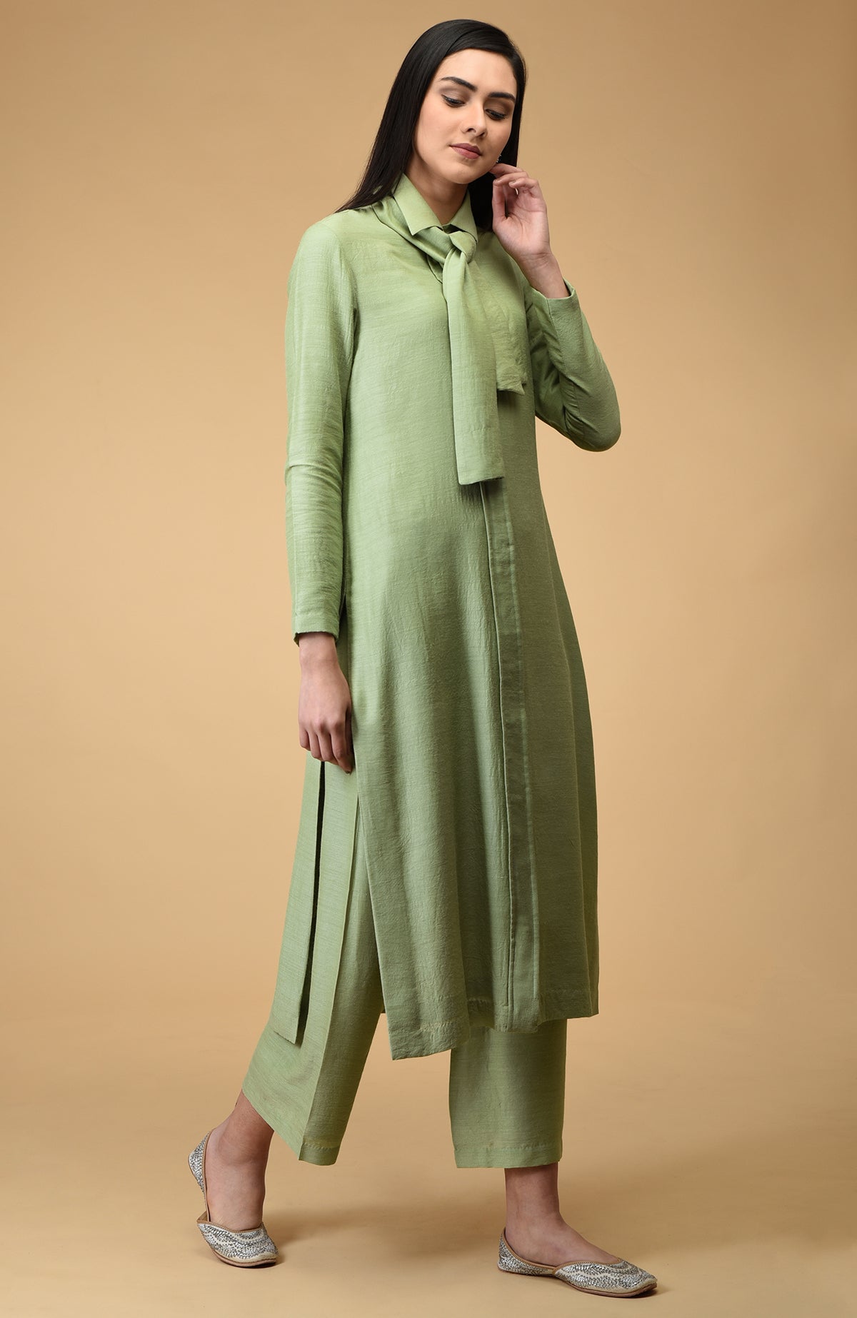 A woman models a sage tie-neck kurta set with embroidered flats.