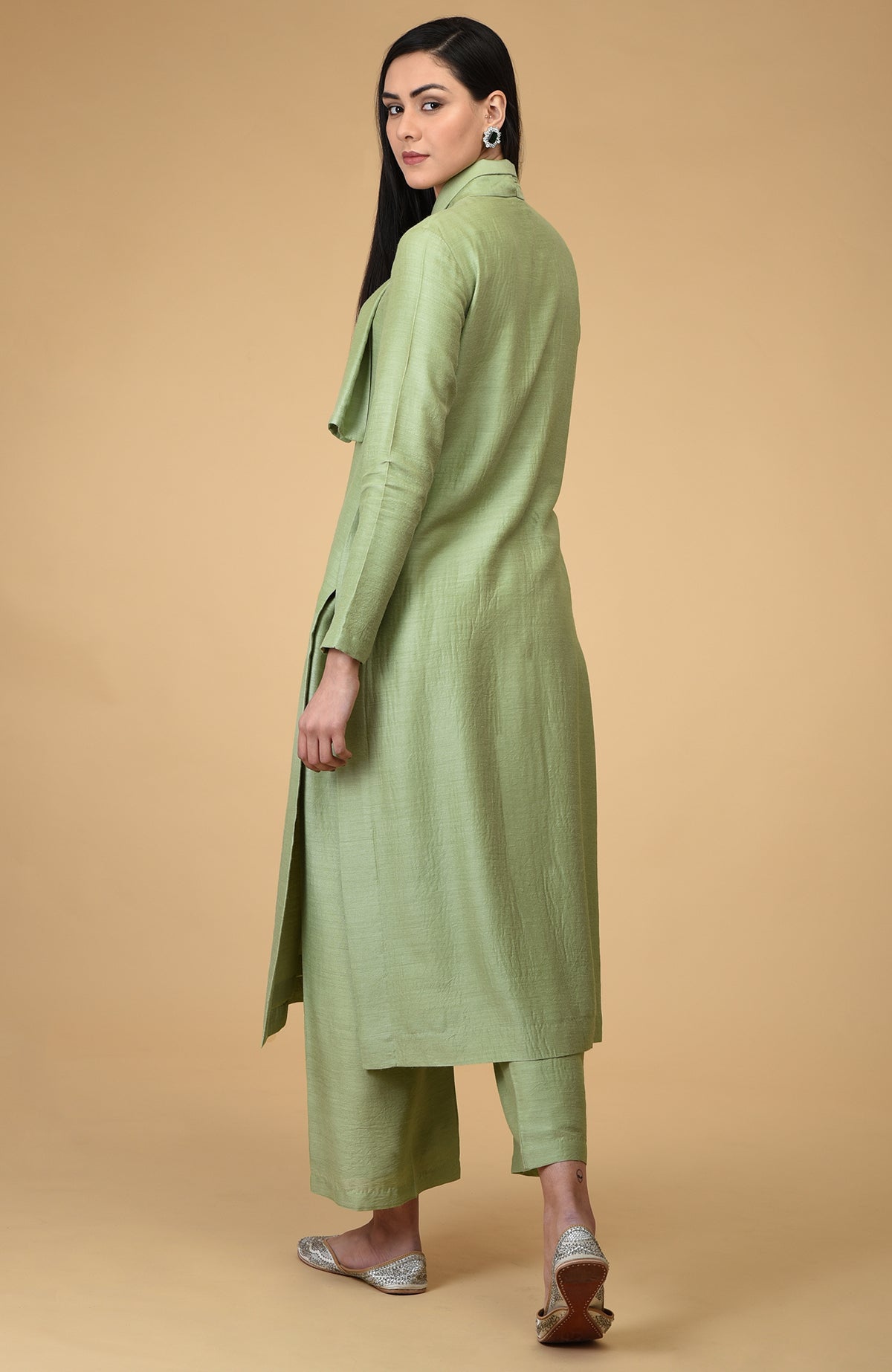 A woman models a sage tie-neck kurta set with wide-leg pants and embellished flats.