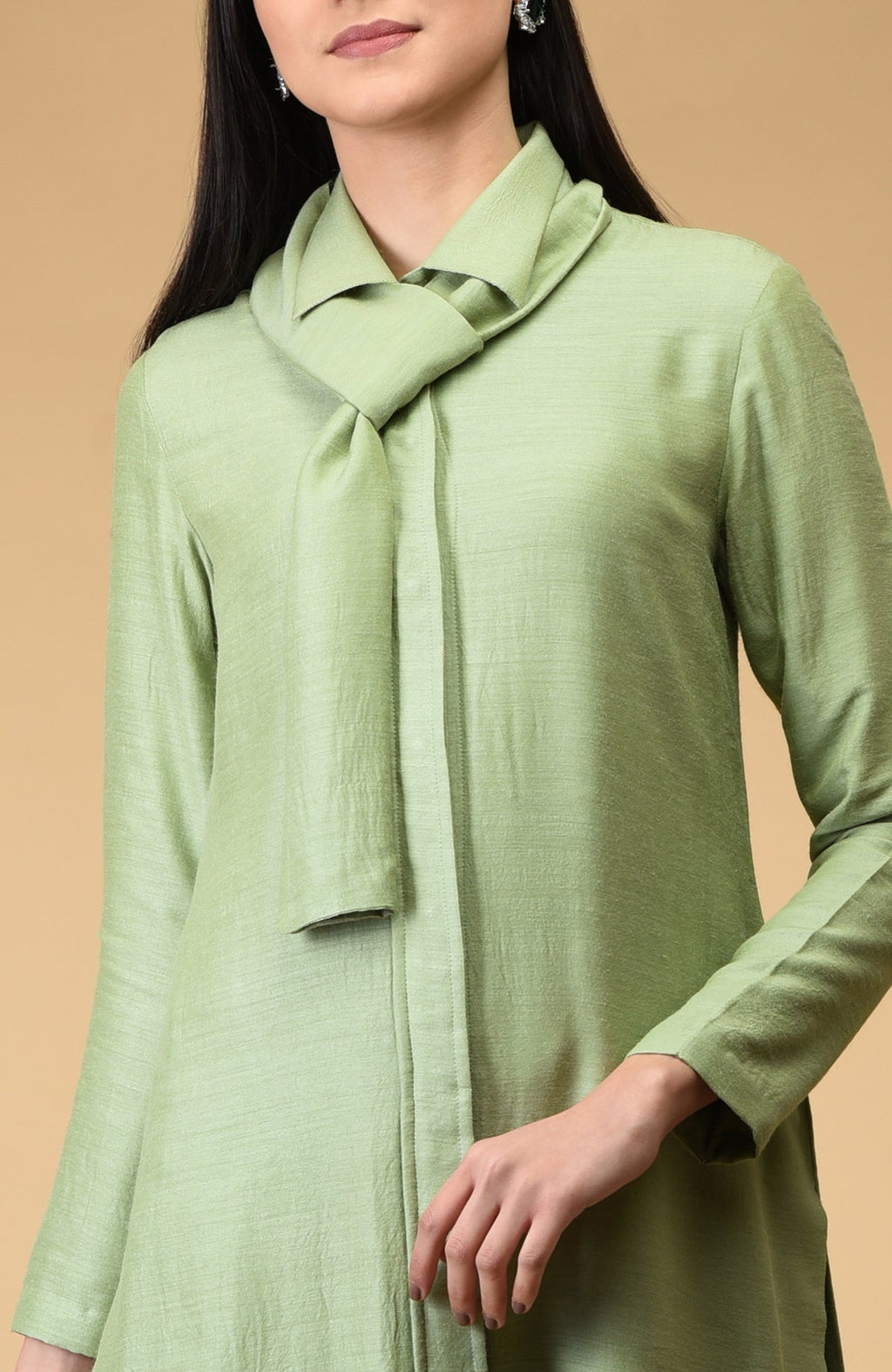 A woman wears a sage green tie-neck kurta with long sleeves.