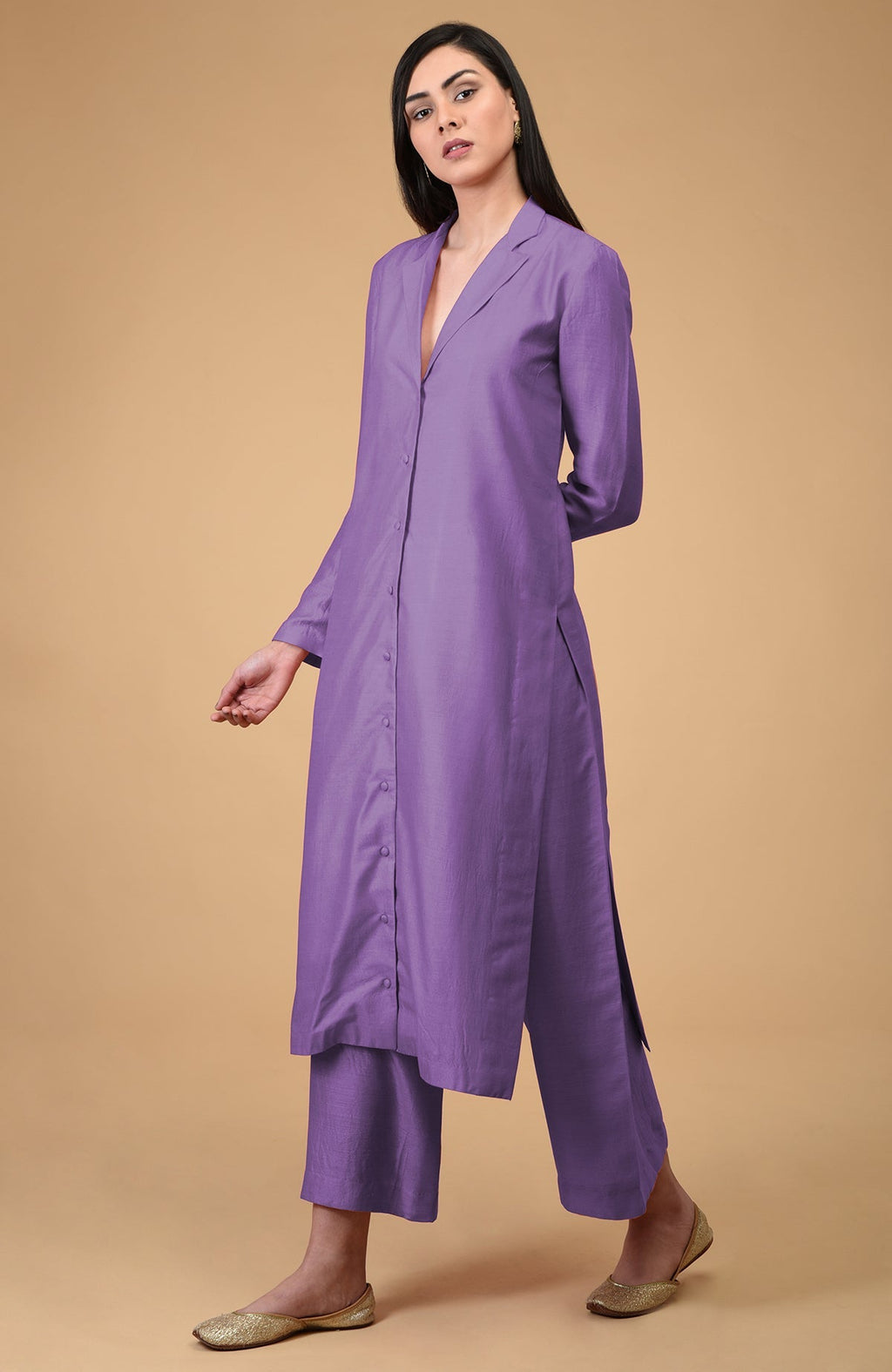 A woman models an amethyst orchid notch collar kurta set with gold flats.