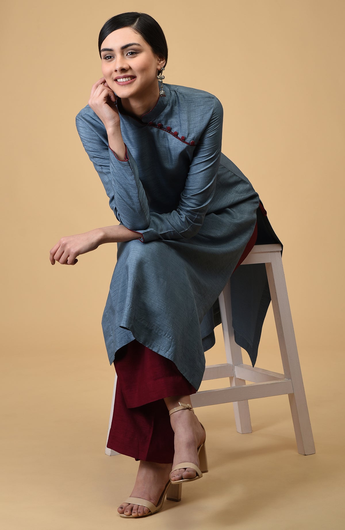 A woman models a blue-grey mandarin collared kurta with maroon wide-leg pants.