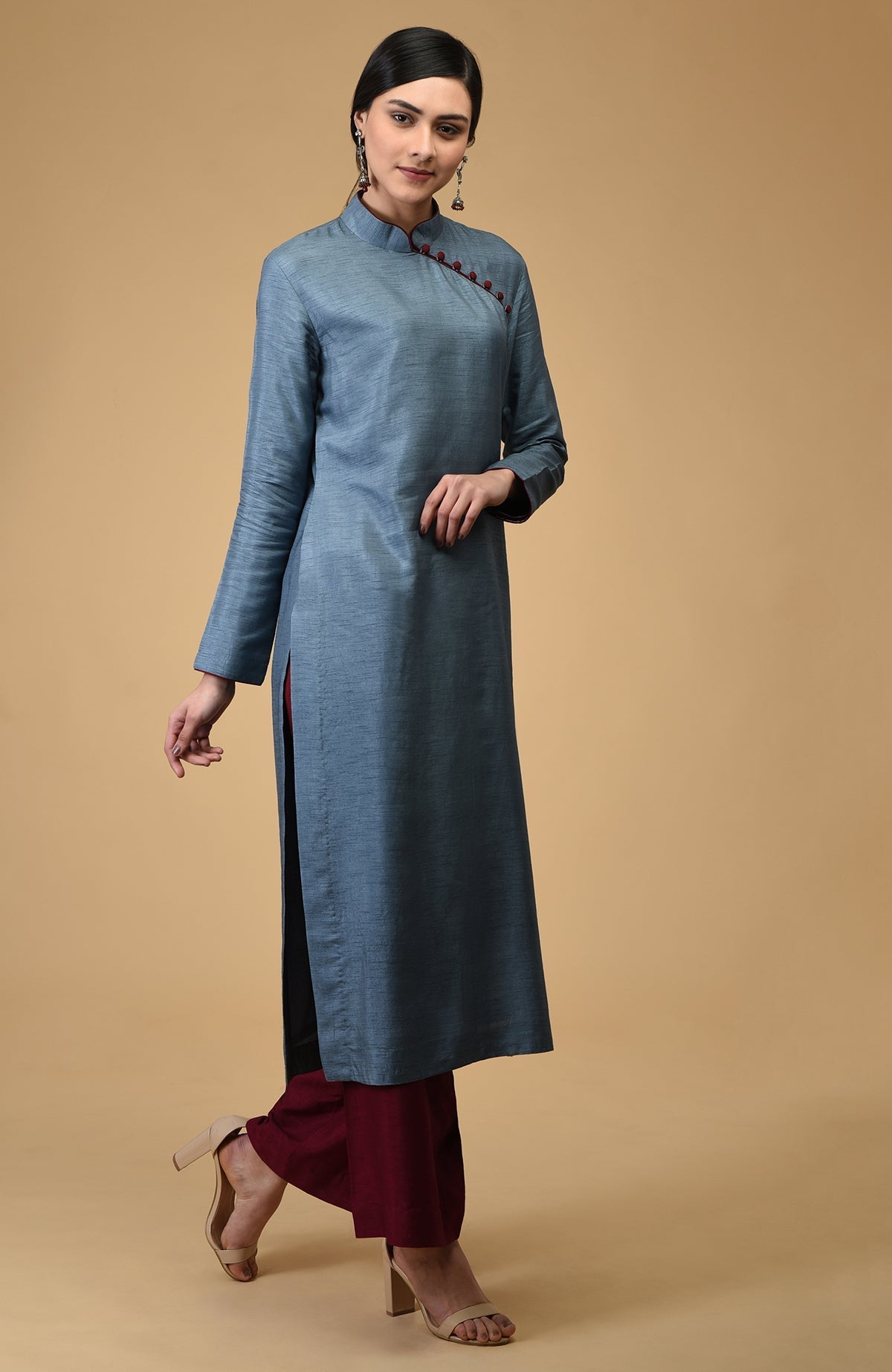 A woman models a blue-grey mandarin collared kurta with maroon wide-leg pants.