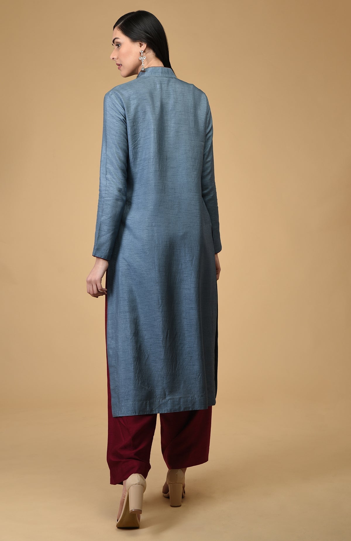 A woman from behind wears a blue-grey mandarin collared kurta and maroon pants.