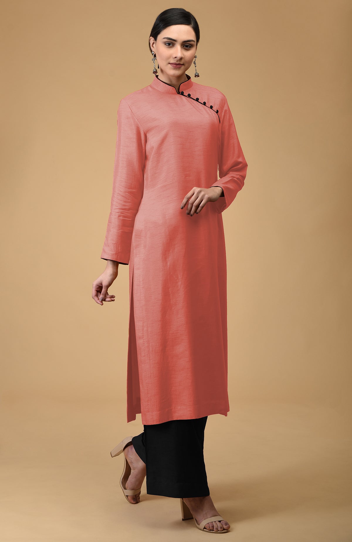 A woman models a terracotta mandarin collared kurta with black pants and nude heels.