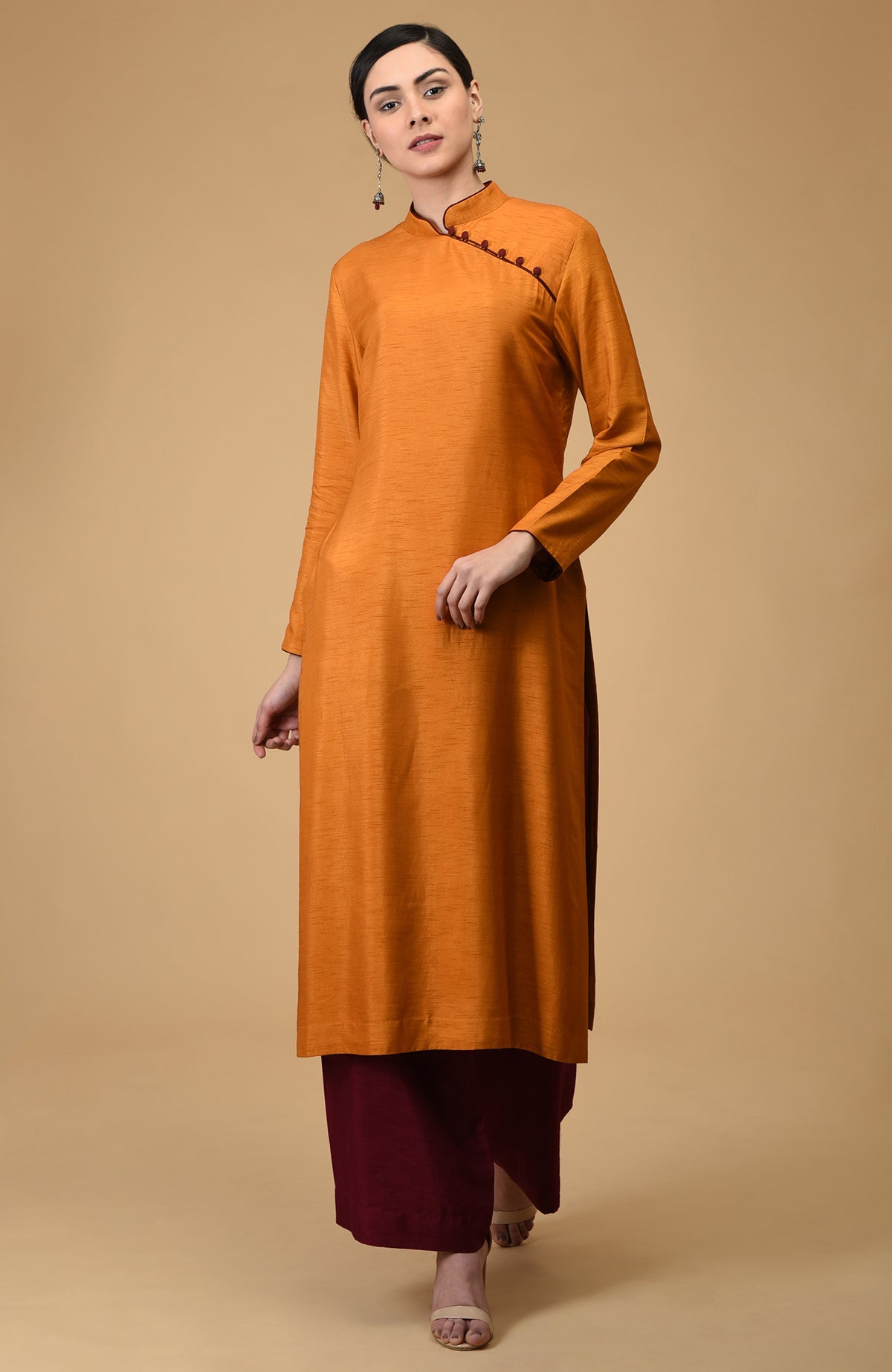 A woman models a terracotta mandarin collared kurta with black wide-leg pants.