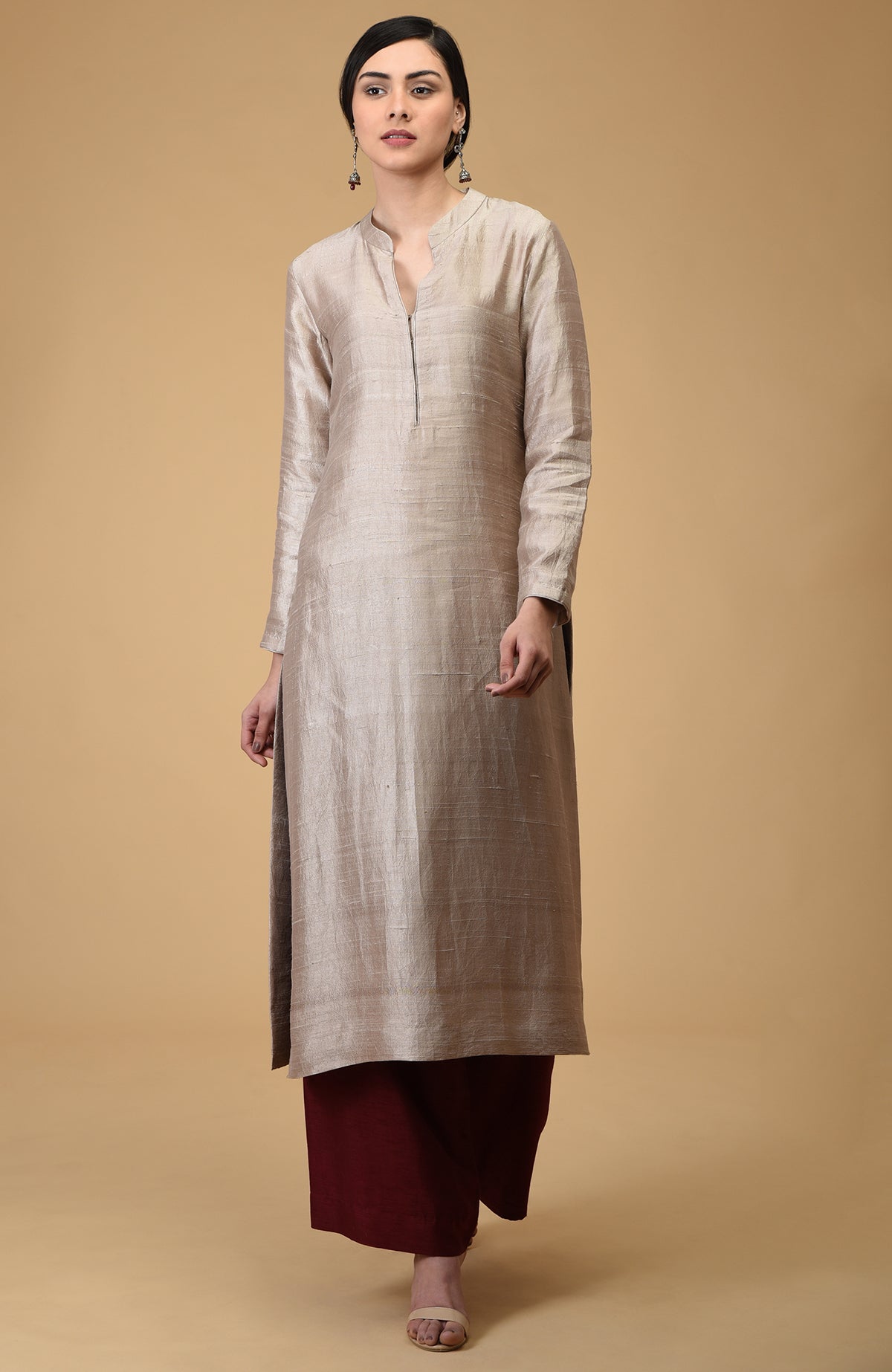 A woman models a beige raw silk kurta with maroon wide-leg pants and sandals.