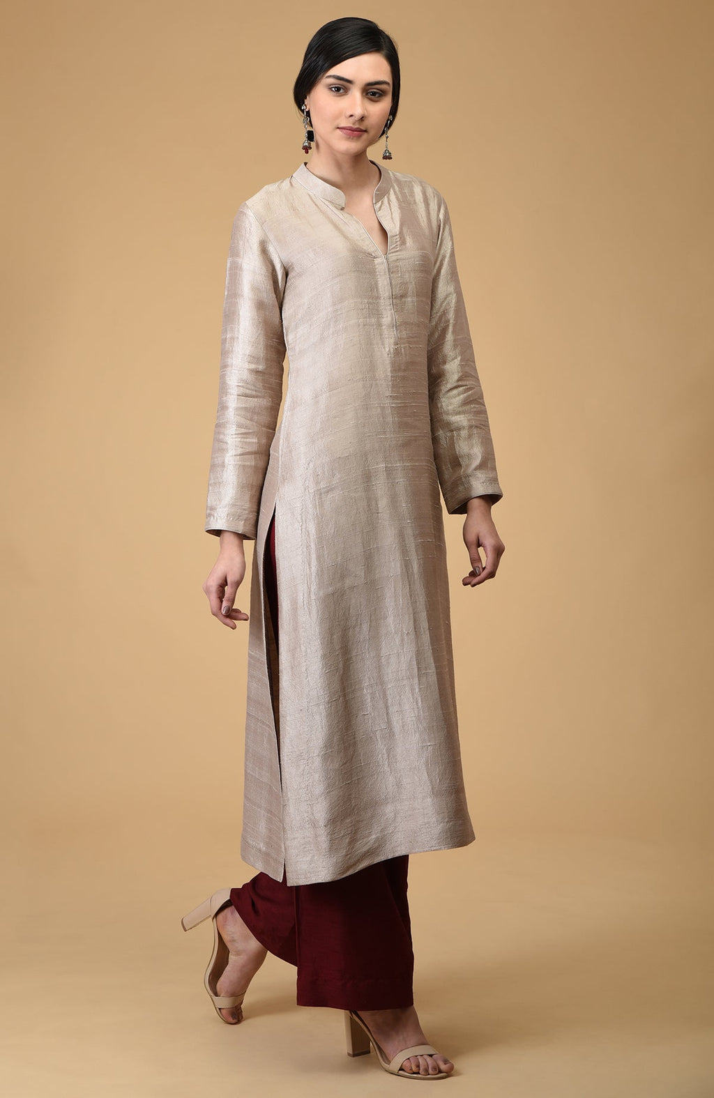 A woman models a beige raw silk kurta with maroon wide-leg pants and nude heels.