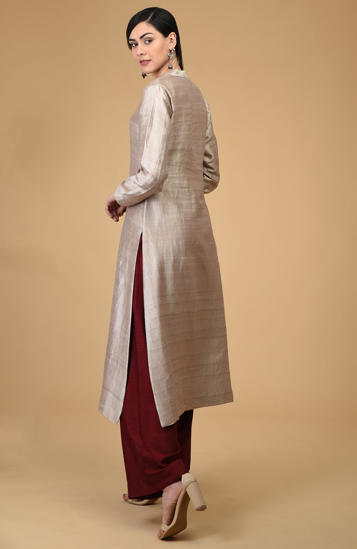 A woman models a beige raw silk kurta with maroon wide-leg pants and heels.