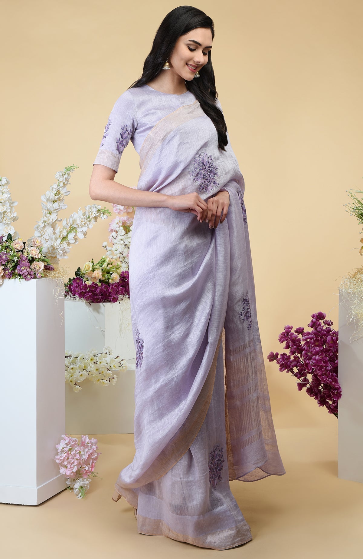 Lilac linen saree with floral embroidery and gold zari borders.