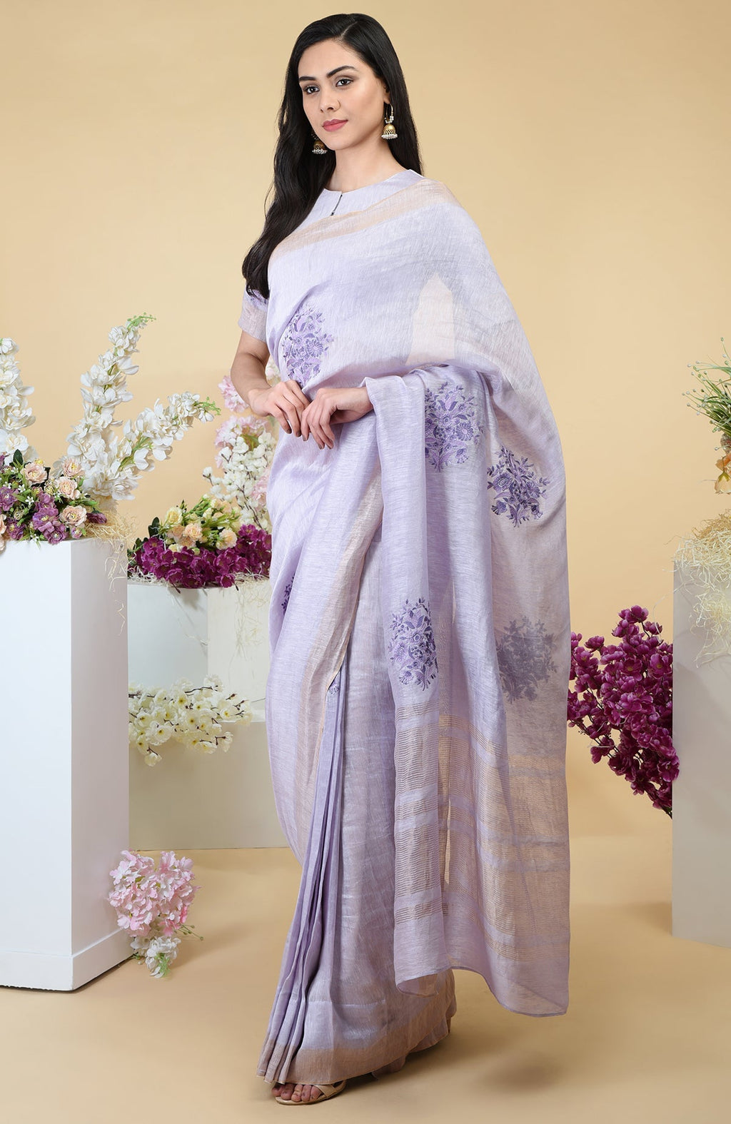 Lilac linen saree with floral embroidery and gold zari weave borders.