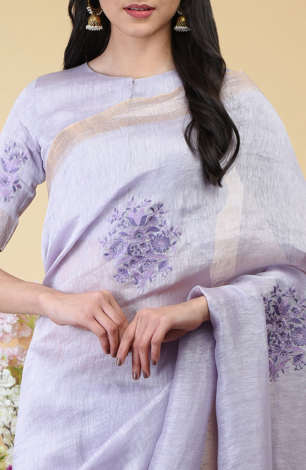 Lilac linen saree with floral embroidery and gold zari borders.