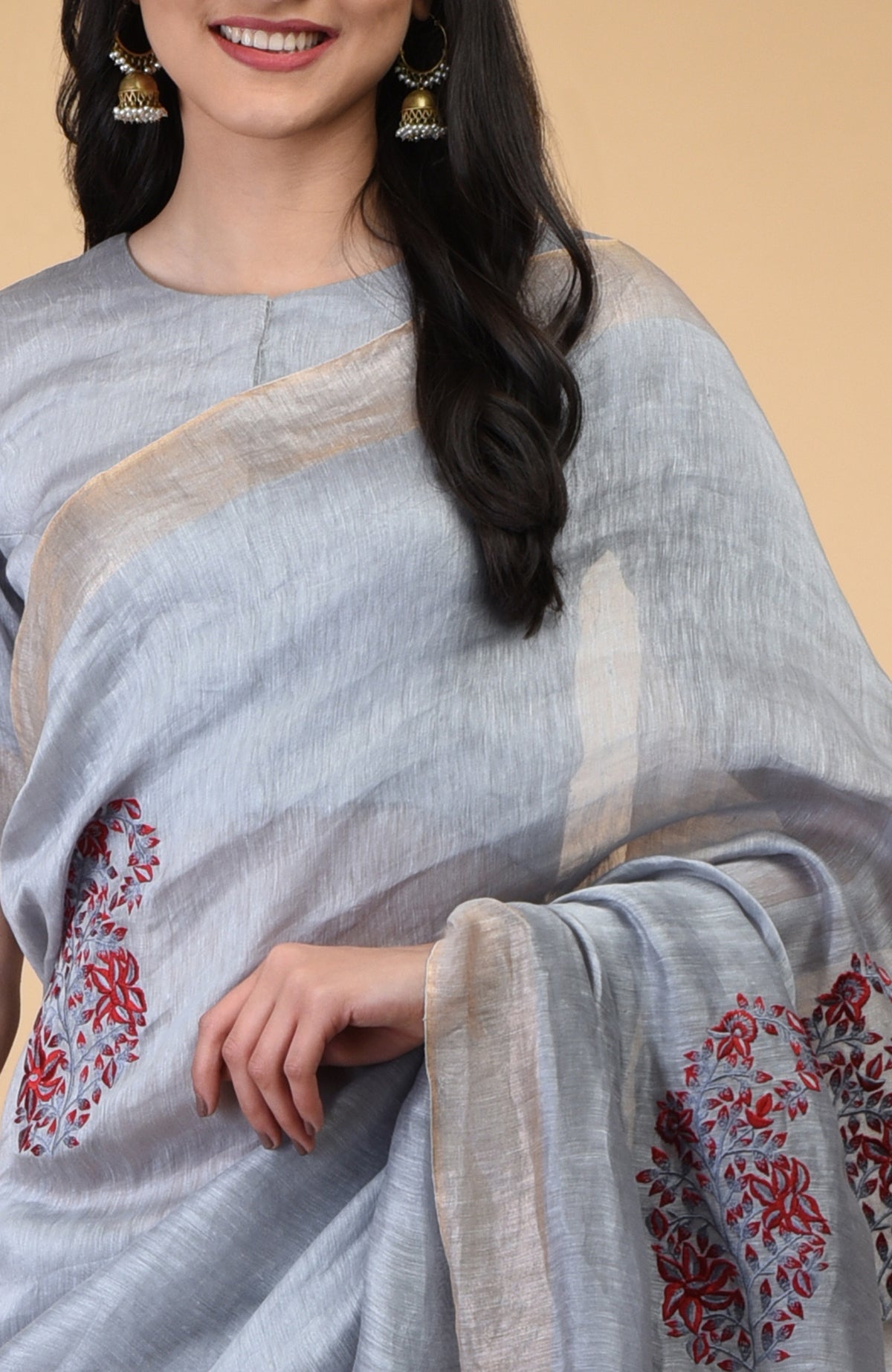 Dove grey linen saree with red embroidered paisley motifs and gold zari borders.