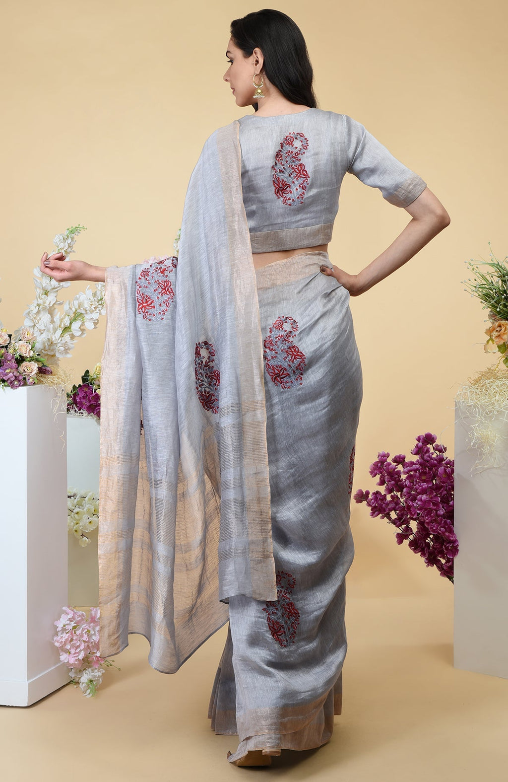 Dove grey linen saree with paisley embroidery and gold zari borders.