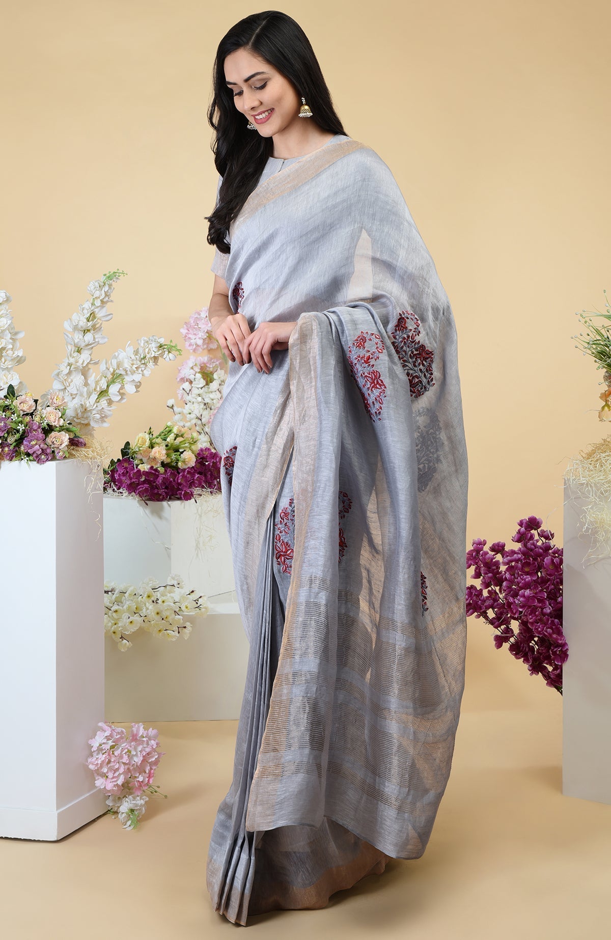 Dove grey linen saree with paisley embroidery and gold zari weave borders.