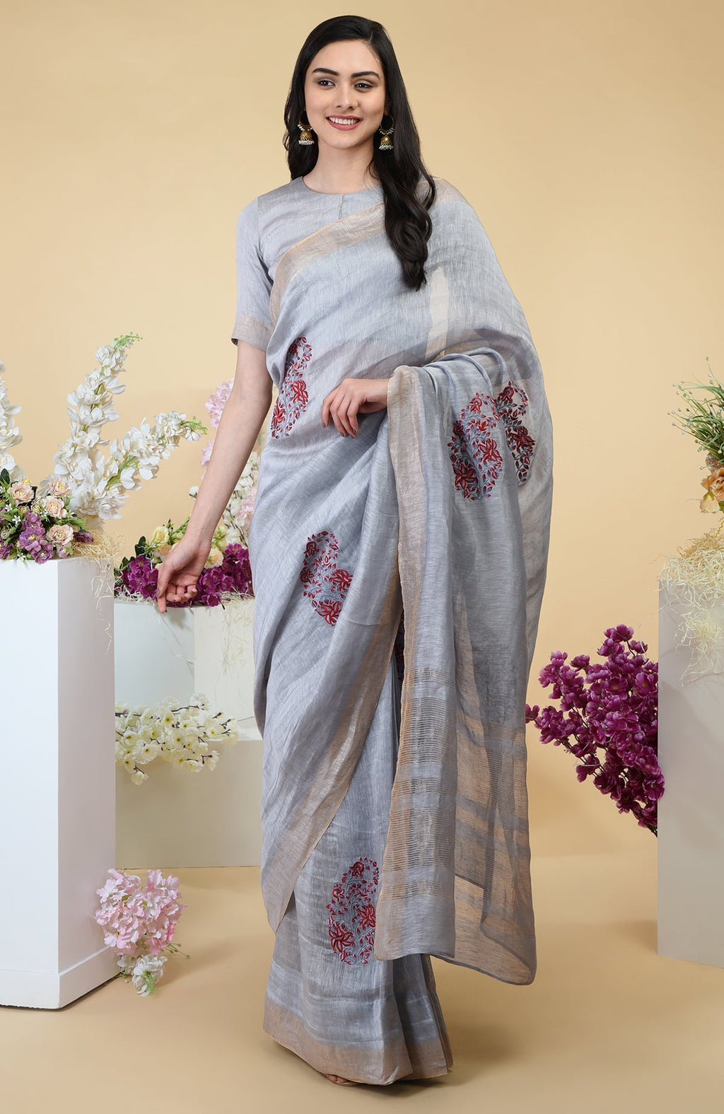 Dove grey linen saree with paisley embroidery and gold zari borders.