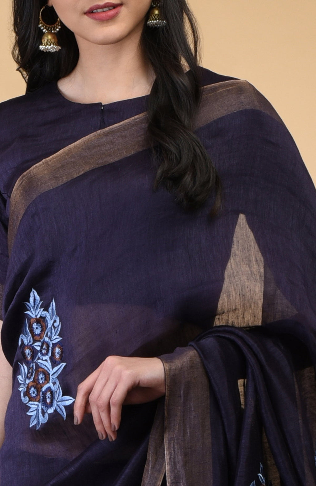 Eclipse blue linen saree with floral embroidery and gold zari borders.