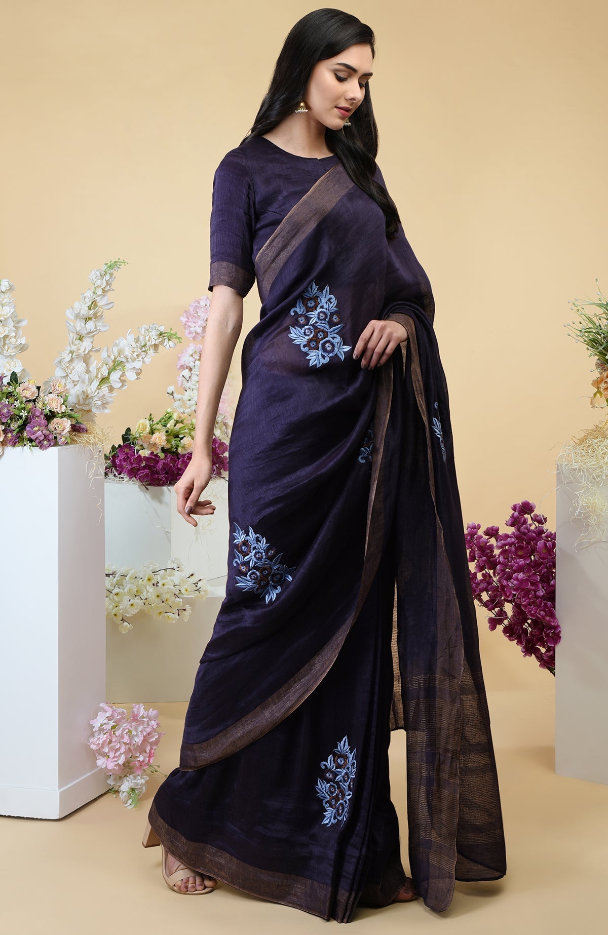Eclipse blue linen saree with floral embroidery and gold zari borders.