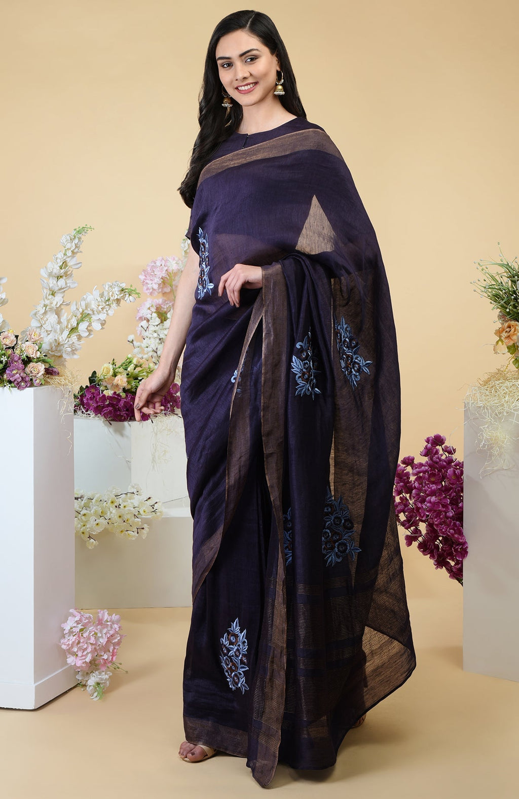 Eclipse blue linen saree with floral embroidery and gold zari borders.