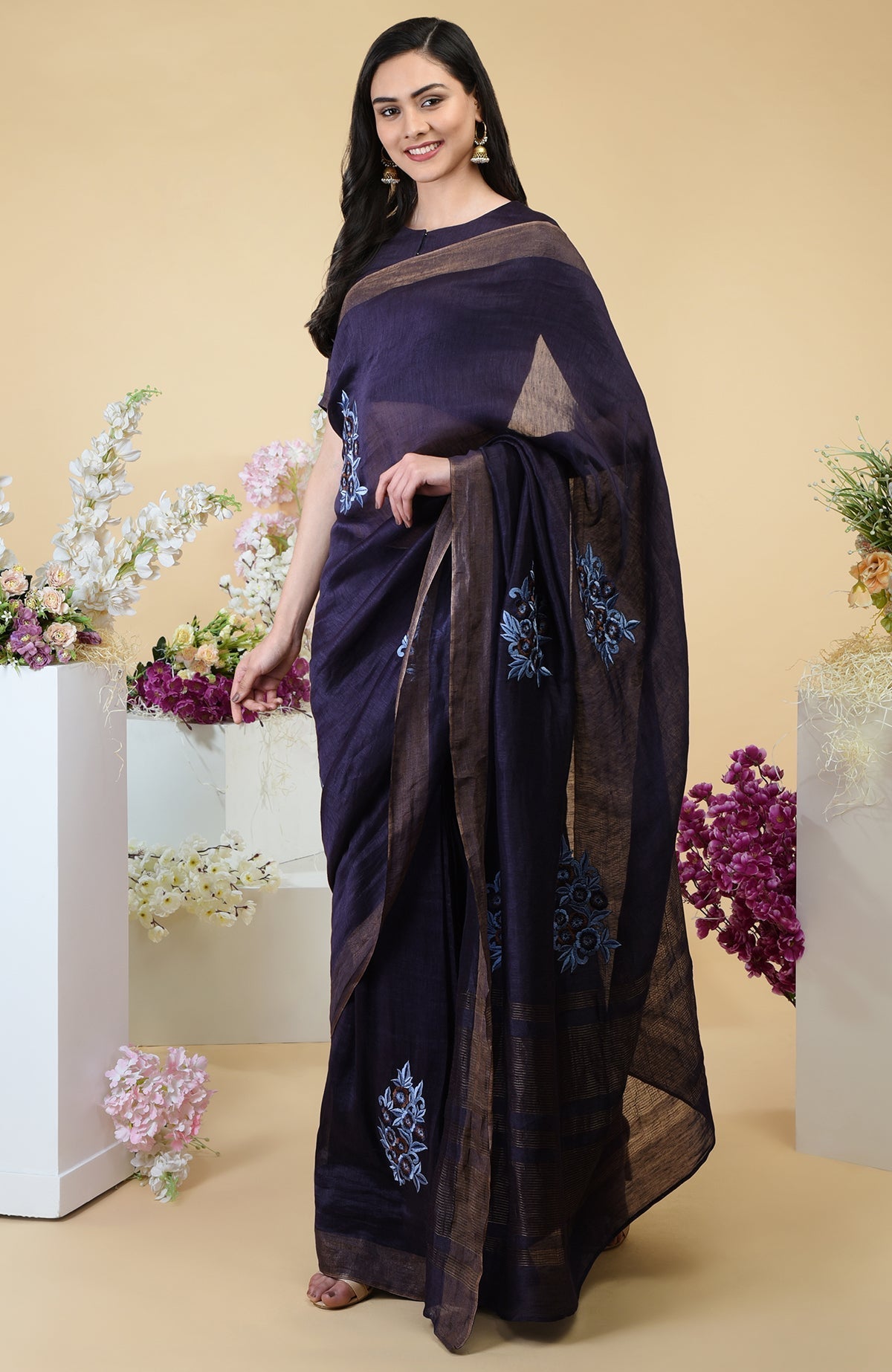 Eclipse blue linen saree with floral embroidery and gold zari borders.