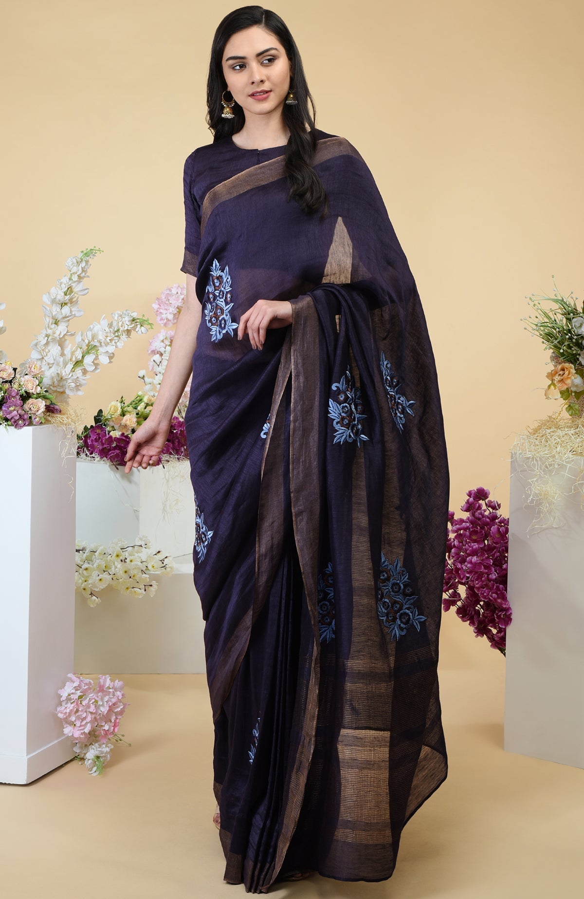 Eclipse blue linen saree with floral embroidery and gold zari borders.