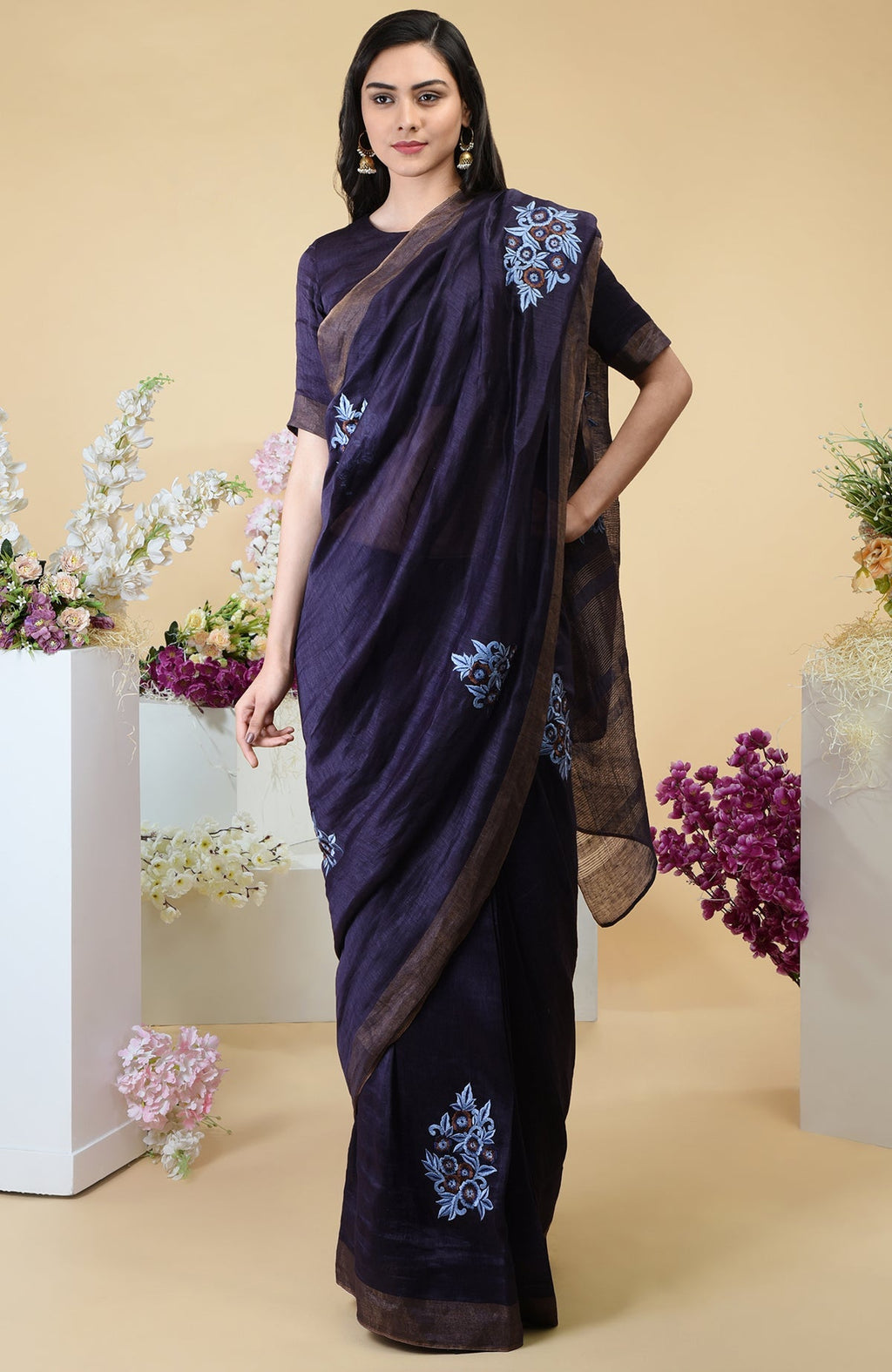 Eclipse blue linen saree with floral embroidery and gold zari borders.