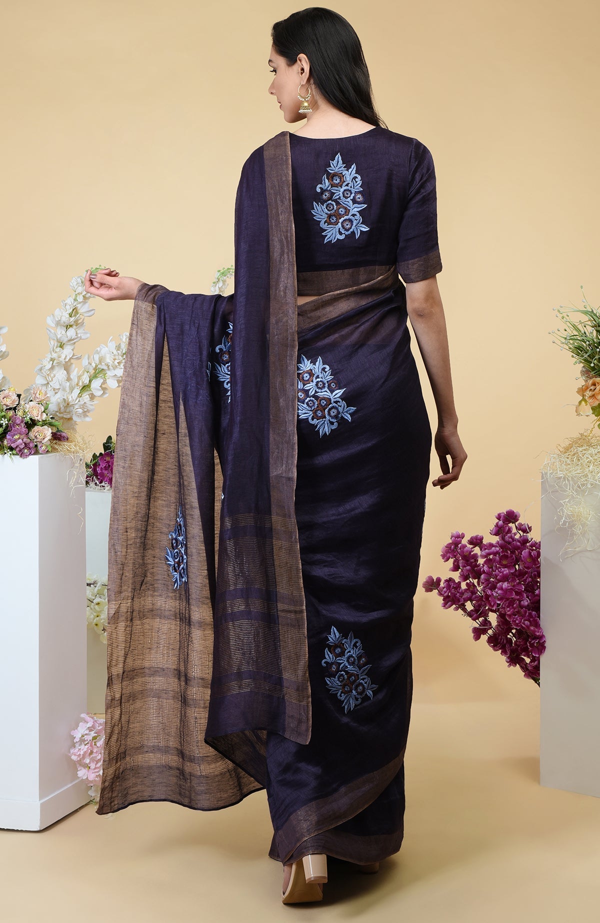 Eclipse blue linen saree with floral embroidery and gold zari borders.