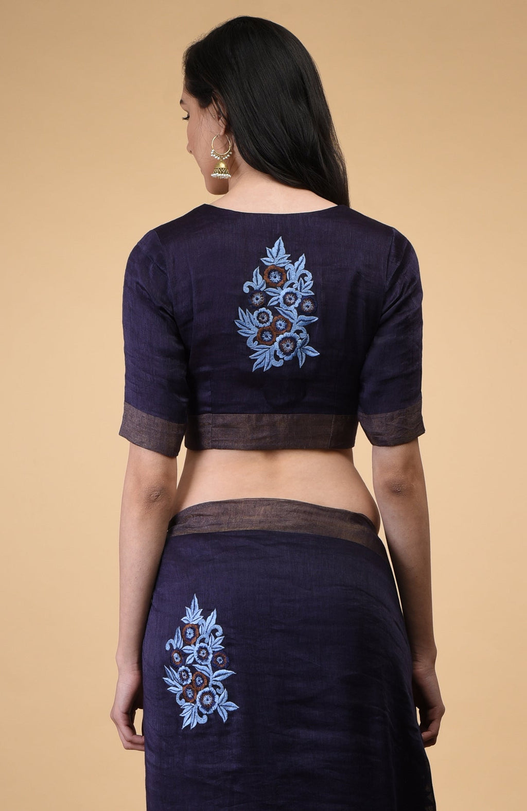 A woman from behind wears an eclipse blue linen saree with floral embroidery.