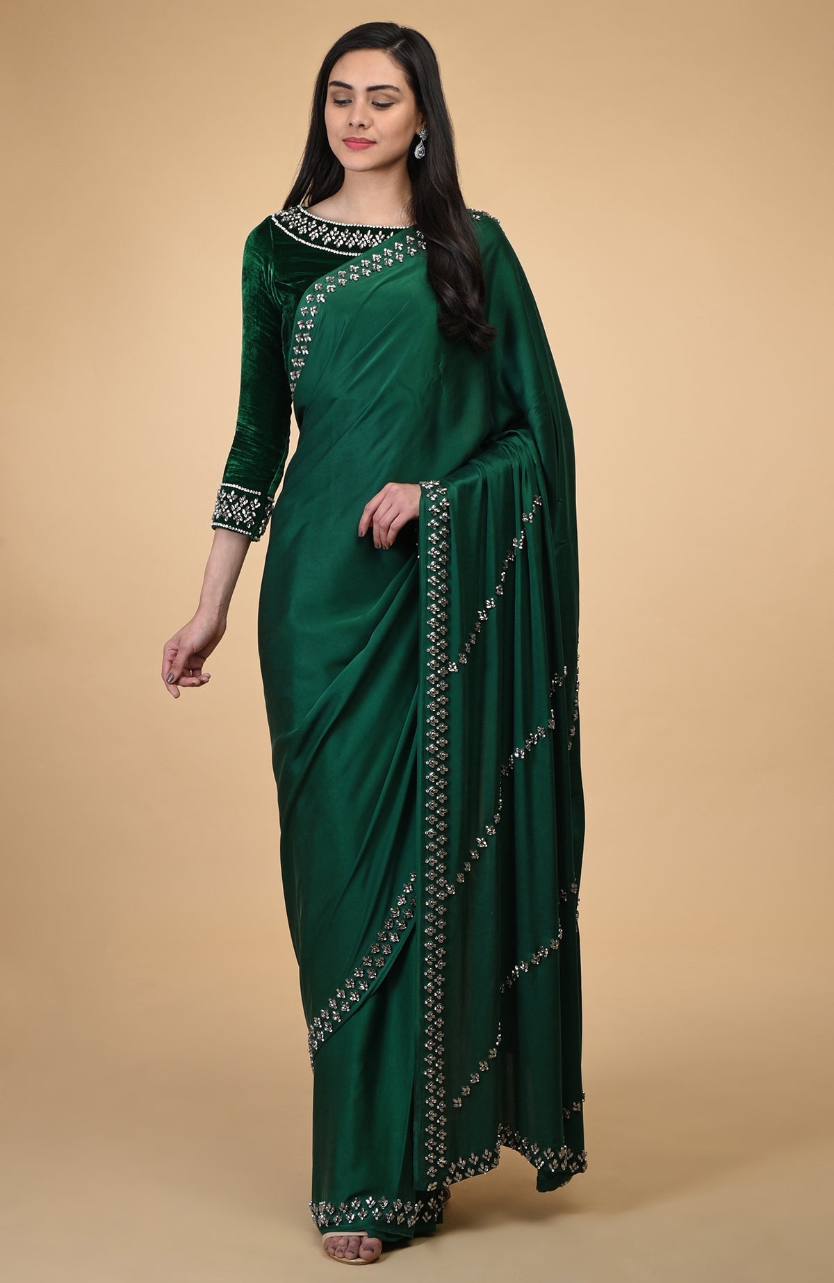 A woman models an emerald green crystal hand-embroidered blouse and matching saree.