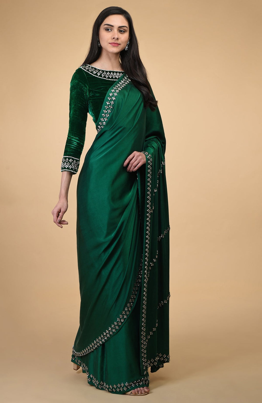 An emerald green crystal hand-embroidered blouse and matching saree are worn by a woman.