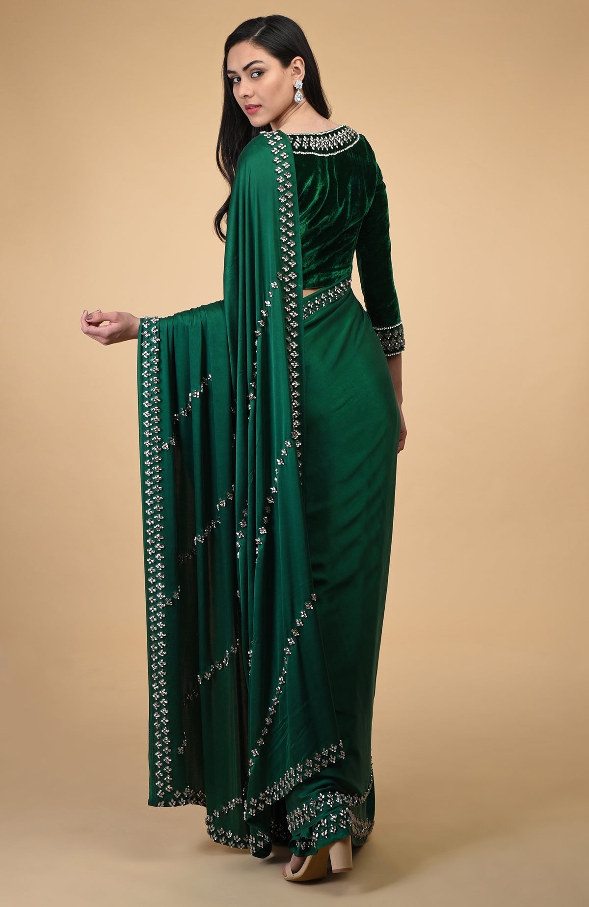 A woman in an emerald green crystal hand-embroidered blouse and matching saree.