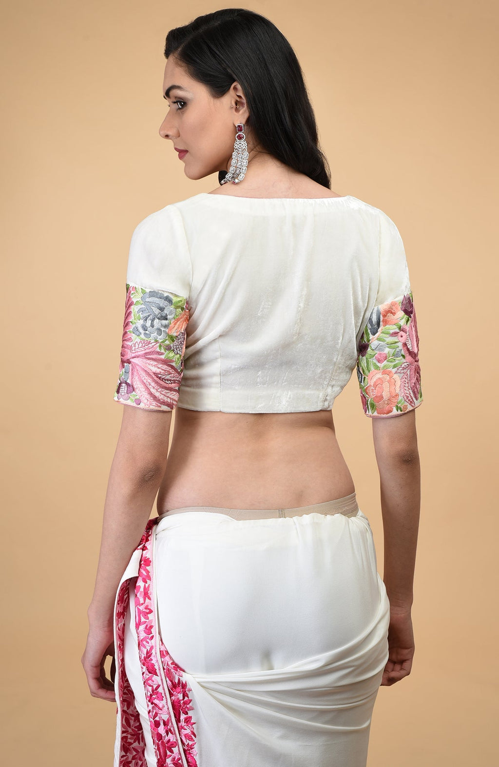 A woman models an ivory Parsi Gara hand embroidered saree with a matching blouse.