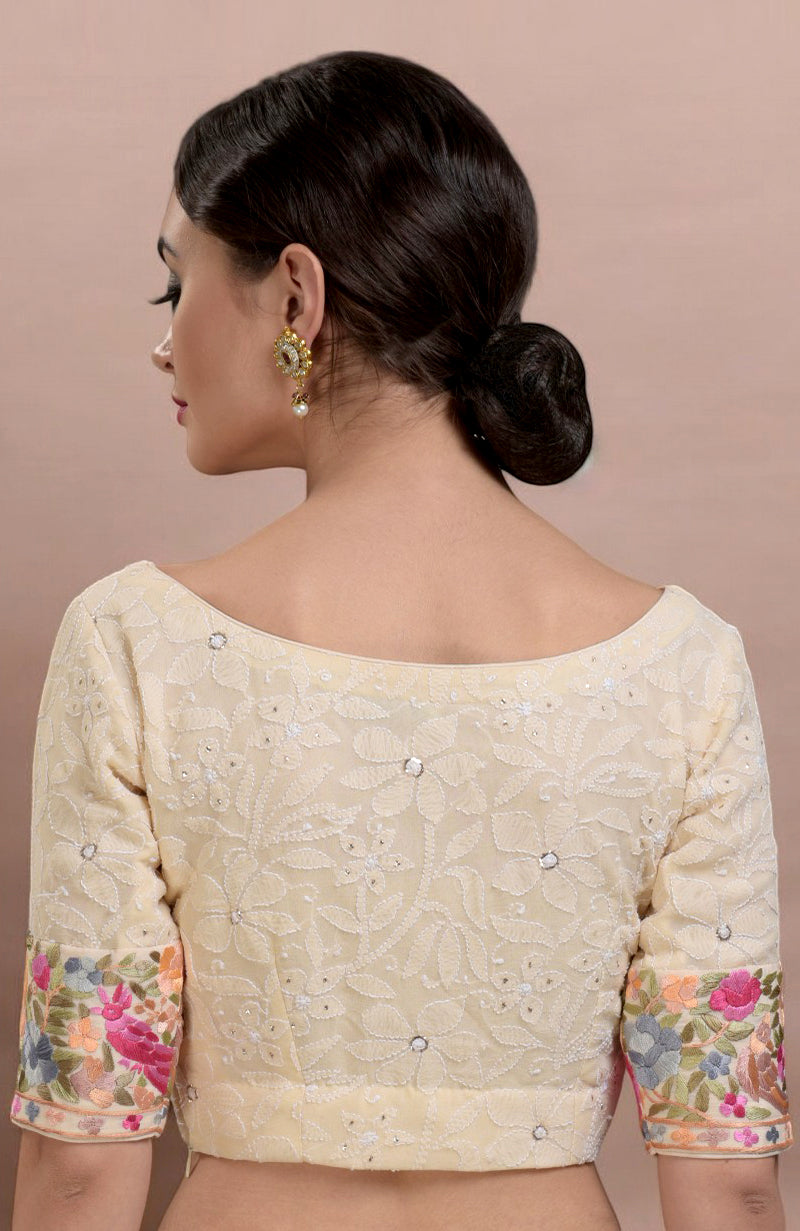 A woman models a champagne chikankari blouse with colorful floral embroidered sleeves.