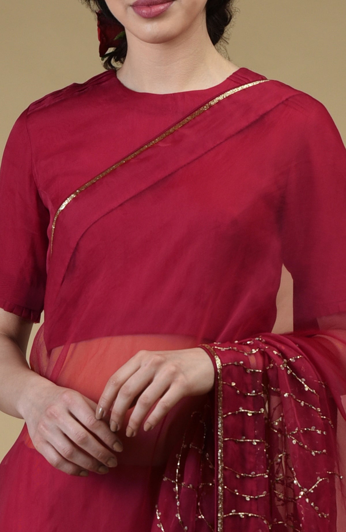 A woman in a red saree with gold bead and sequin embroidery.