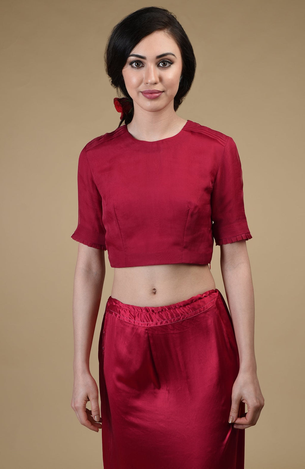A woman models a red crop top with pleated sleeves and matching red pants.