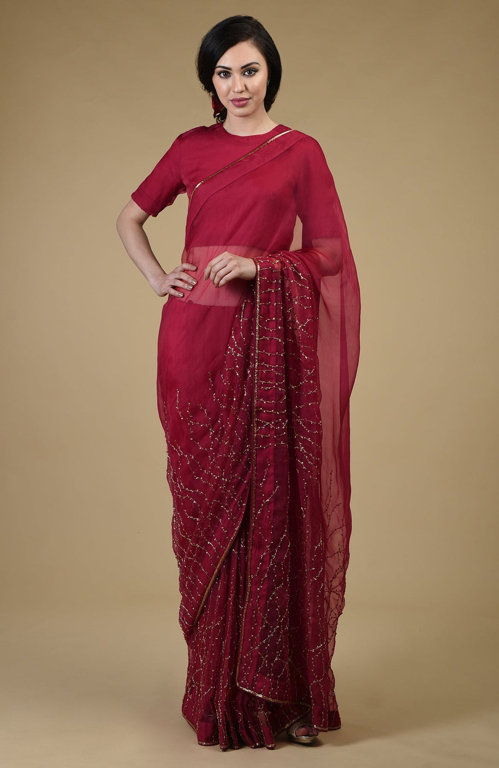 A woman models a red-gold beads and sequin zardozi hand-embroidered saree.