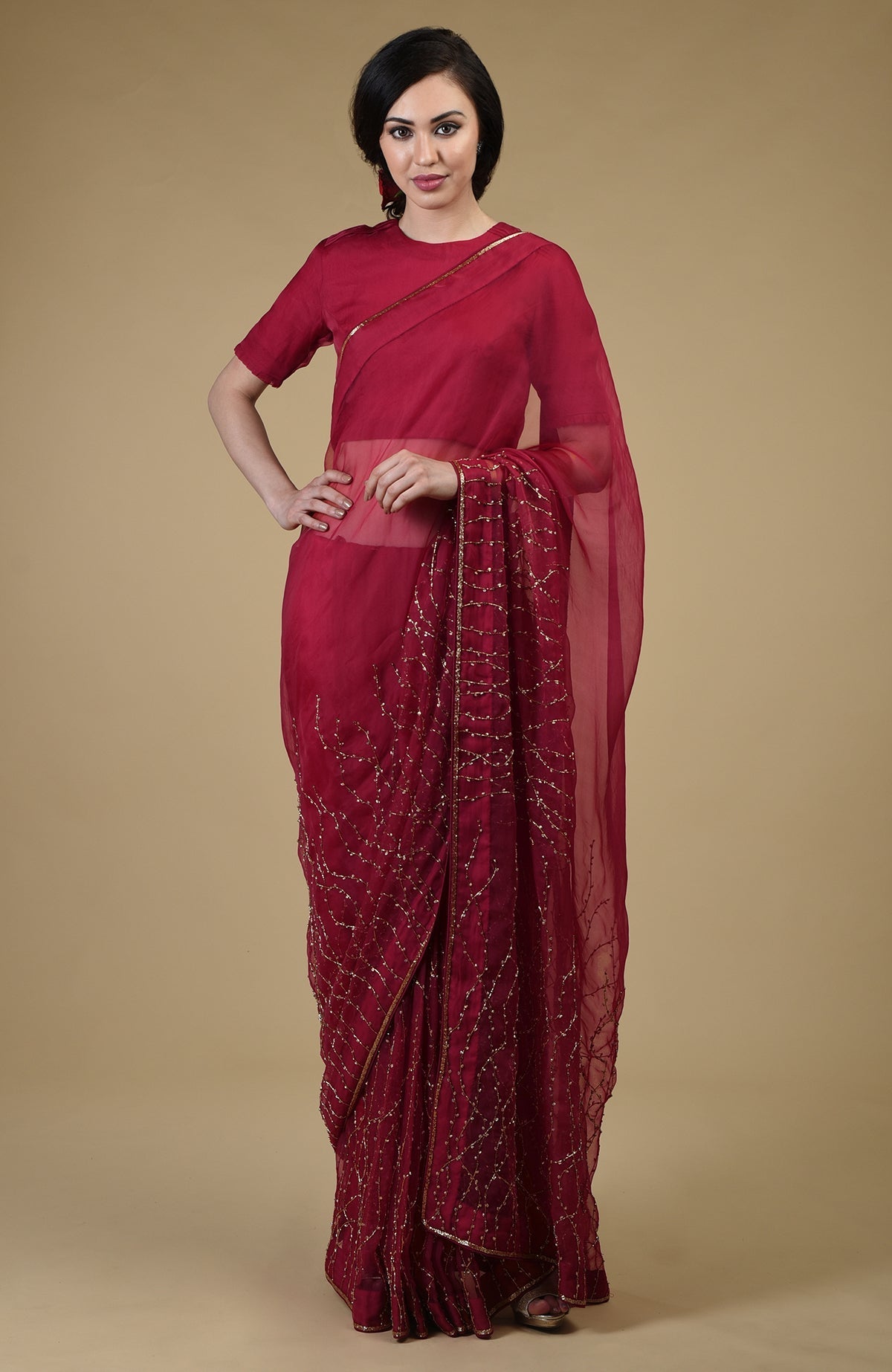 A woman models a red-gold beads and sequin zardozi hand-embroidered saree.