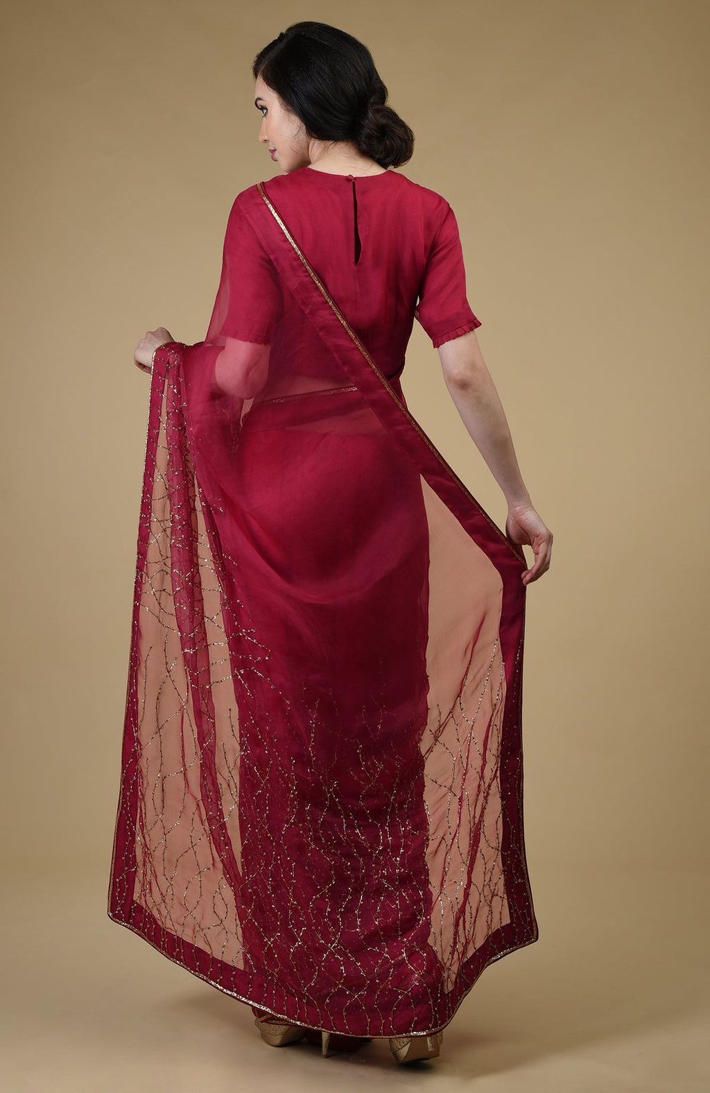 A woman in a red-gold beads and sequin zardozi hand-embroidered saree.