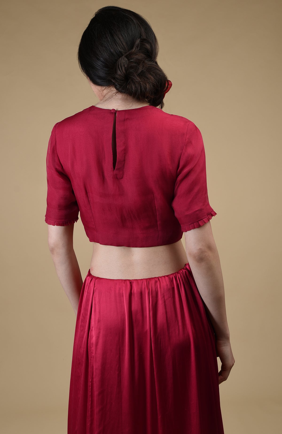 A woman from the back wearing a red blouse with a keyhole opening and a red skirt.