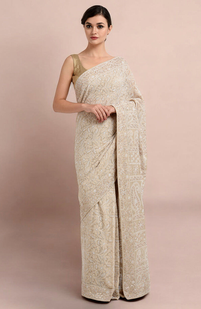 A woman models a champagne Lucknowi Chikankari and Gota Patti hand-embroidered saree.