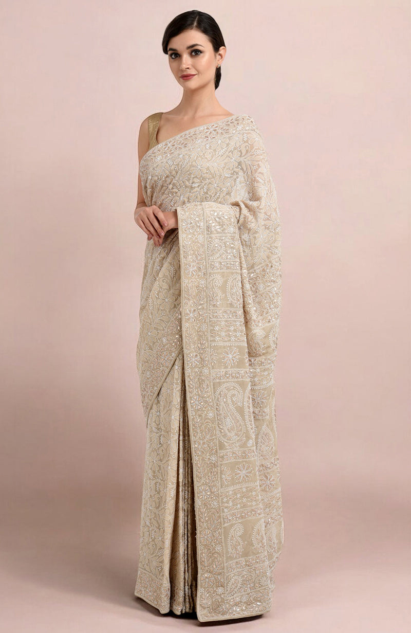 A woman models a champagne Lucknowi Chikankari and Gota Patti hand-embroidered saree.